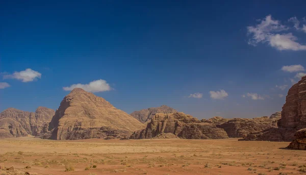 Öken landskap pittoreska berg pyramid form sand sten utbud runt sand dal i Wadi Rum Jordanien Mellanöstern natur natursköna Unesco världsarv destination tapet bakgrund kopiera utrymme — Stockfoto