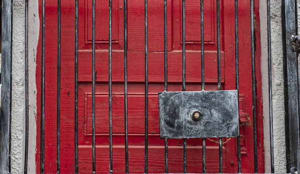 red door frame behind steel grid closed entrance textured background