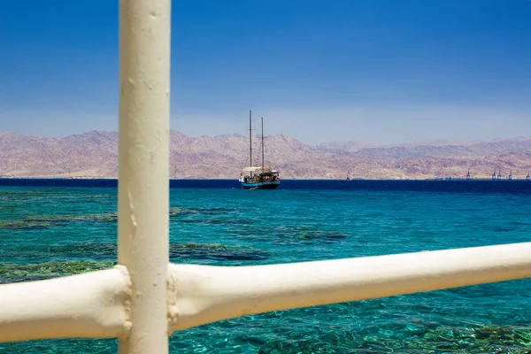Cruise ship floating on Red sea aquamarine transparent water with coral riffs view on bottom through white fence pipes frame, summer vacation photography — Stock Photo, Image