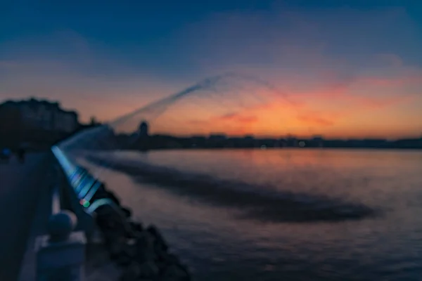 Неориентированные сумерки освещения открытых водохранилищ набережной пешеходный район с фонтанами силуэт потока на вечернем фоне заката, копировальное место — стоковое фото