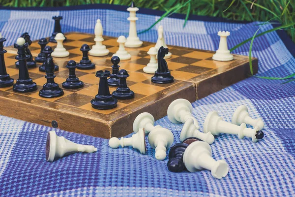 Escritorio de ajedrez clásico de enfoque suave sobre fondo y figuras caídas en blanco y negro en primer plano en espacio de copia de textura de alfombra azul — Foto de Stock