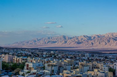 Çöl manzaralı şehir manzarası ön planda küçük binalar ve perspektifli kum tepesi arka planında yaz sabahı güneş doğumu zamanı mavi gökyüzü, kopyalama alanı
