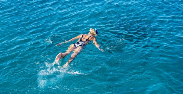 Yaz tatilinde deniz mavisi içinde yüzen bir kadın.