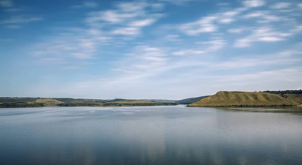 picturesque summer time morning landscape of peaceful lake reservoir water surface horizon background national park hill land and blue sky cloudy fuzzy motion concept effect