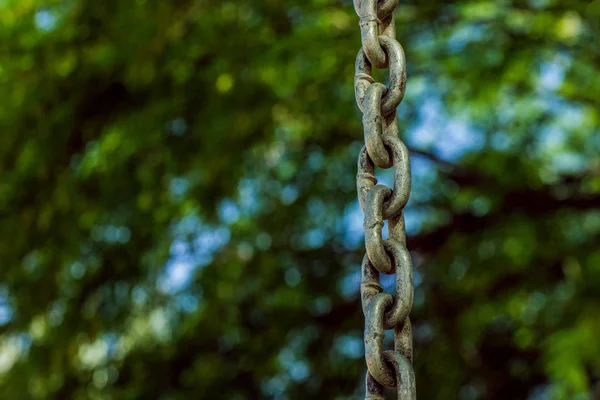 Dangerous for ecology concept photography pattern of old iron chain hanging on unfocused blurred natural green park outdoor background, empty copy space for text or inscription — Stock Photo, Image