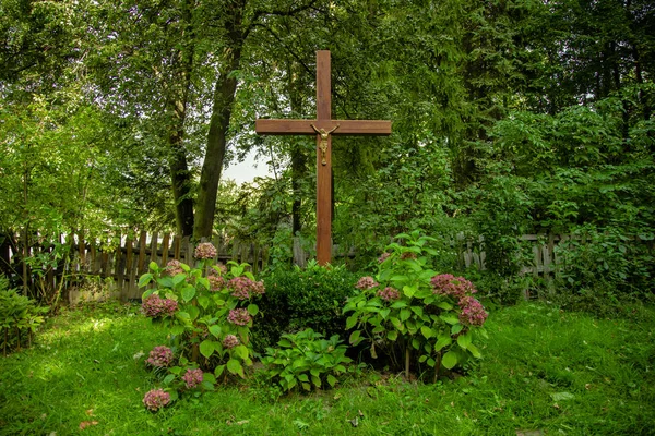 Religion cross cemetery grave landscaping view ground hill flower bed vivid green grass cover spring time blooming garden peaceful nature environment on forest edge — Stock Photo, Image