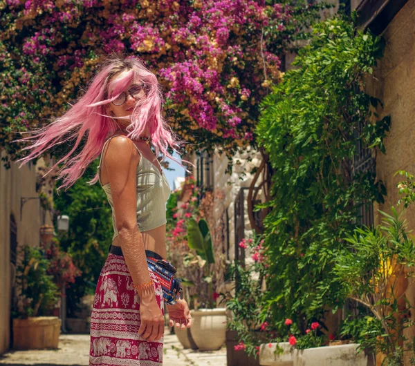 Kvinnligt porträtt av ung kvinna rosa hår vända sig om rörelse i trädgården våren tid blomma stad gata med färgglada blommor miljö — Stockfoto