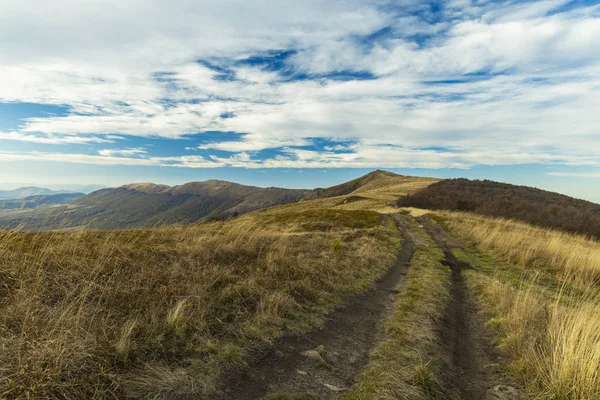 highland mountain ridge dirt trail route scenic landscape view horizon background cloudy blue sky