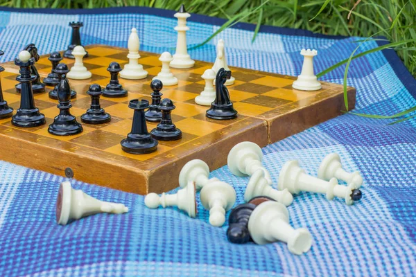 Escritorio de ajedrez clásico de enfoque suave sobre fondo y figuras caídas en blanco y negro en primer plano en textura de alfombra azul — Foto de Stock