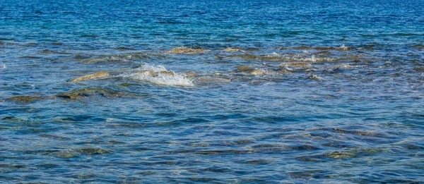 Panoramica blu acqua fondo superficie con pietra e spruzzi di mare paesaggio vista panoramica — Foto Stock