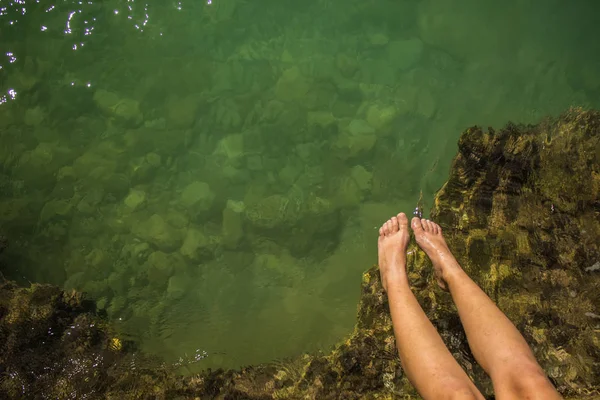 Atividades do mar de verão e fotografia aérea conceito hobby com snorkeling máscara de equipamento e tubo perto da mão da mulher e pés descalços na orla de pedra e fundo de superfície de água transparente — Fotografia de Stock