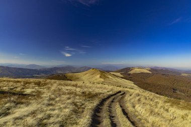 Highland Hills Dağları manzarası. Baharın ilk zamanlarında kahverengi zemin. Kirli yalnız patika ve mavi gökyüzü ufku.