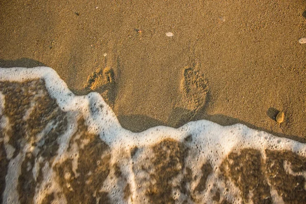 Морская линия песчаной набережной и отпечаток человеческой ноги частично под нечеткими волнами обои концепции туристического агентства с пустым пространством для копирования или текста — стоковое фото