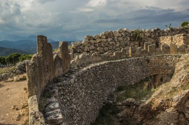 Avrupa kırsalındaki antik harabe taş kale binasının arkeolojik sahasının arka planında dağ manzarası var.