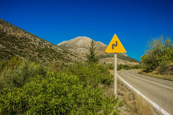 Prázdný auto silniční infrastruktura symboly koncept žluté znamení odbočit na malebný horský les vysočina příroda prostředí — Stock fotografie