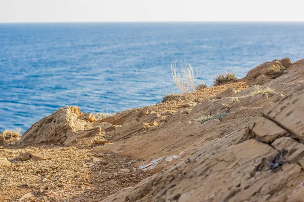 Tropic beach in one of south countries concept view of soft focus yellow stones texture on top of rocks and unfocused water surface with waves background — Stock Photo, Image