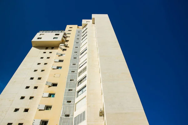 Common ordinary concrete living building modern city architecture object window wall exterior facade foreshortening from below on vivid blue sky background space — Stockfoto