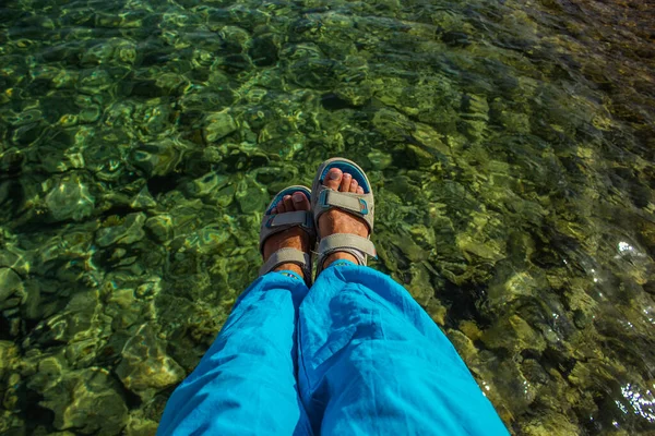 Piedi maschili sandali e pantaloni blu selfie vista dall'alto con serbatoio acqua di fondo — Foto Stock