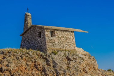 small catholic church on top mountain rock nature landscape pilgrim place on blue empty sky background