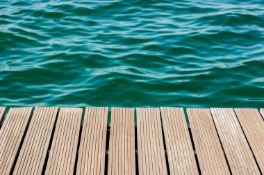 wooden deck floor waterfront shoreline background texture material perspective foreshortening surface to blue water, wallpaper pattern for copy or text