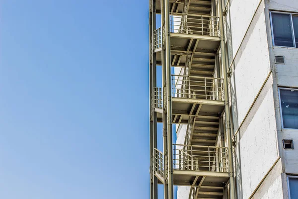 Metal fire escape stairs construction outdoor side of high building and empty blue sky, copy space — ストック写真
