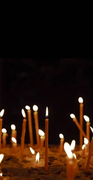 Candle yellow illumination religion spiritual atmospheric praying concept in vertical picture black background empty copy space for your text here — Stock Photo, Image