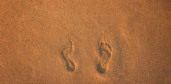 Vacances d'été concept plage de sable fond simple surface texturée empreintes de pieds humains sur un motif de papier peint vue du dessus du sol pour l'agence de voyage espace de copie vide pour votre texte ici — Photo