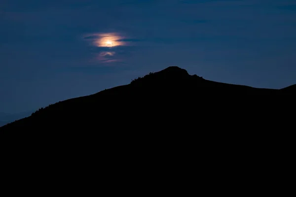 Μαύρο βουνό σιλουέτα χρόνο φάντασμα μπλε νύχτα ουρανό σκοτεινό αφηρημένο τοπίο φόντο ταπετσαρία γραφική θέα με μη εστιασμένη φεγγάρι πίσω από σύννεφα κενό χώρο αντίγραφο για το κείμενό σας εδώ — Φωτογραφία Αρχείου