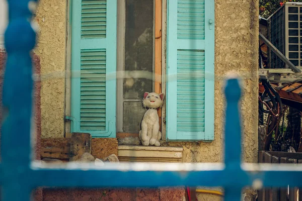 Hinterhof Außengarten Raum der Stoffkatze auf Fensterbank mit offenen Rollläden Außenbild mit blauem Metallzaun und Gitter Vordergrundrahmenarbeit — Stockfoto