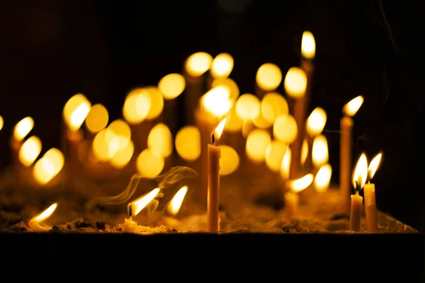 Kerzen in dunkelgelber Feuerflamme und unkonzentriertem Bokeh Hintergrund religiöses spirituelles atmosphärisches Bild — Stockfoto
