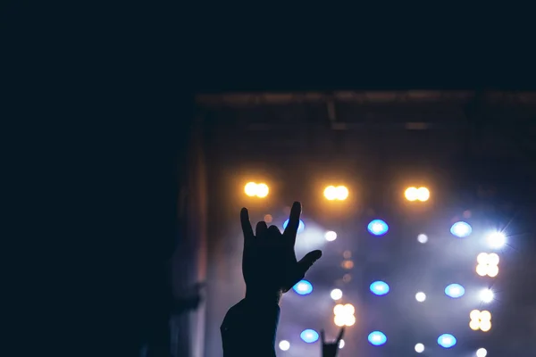 Rock konsepti performansı insan eli ile müzik altkültürü ile işaret ile karanlık sahne renkli aydınlatma poster konsepti için odaklanmamış arka plan alanı — Stok fotoğraf