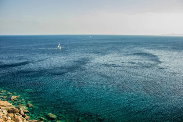 beautiful tropic panorama of small yacht on vivid blue water sea surface background near rocks shore line landscape view from above aerial shot, copy space for your text here