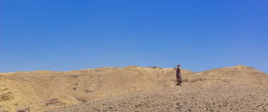 Çöl kuru ıssız arazide yalnız bir kadın hiçbir şeyin ortasında yalnız kalır kum taşları tepeleri manzaralı ufuk arkaplanı canlı mavi gökyüzü boş metin alanınız için