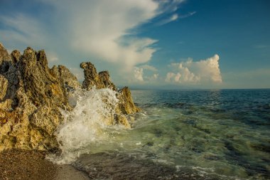 Deniz kıyısı küçük kayalar ve dalgalar taşların üzerinde kırılır Akdeniz yaz tatili için hava durumu duvar kağıdı ya da afiş için