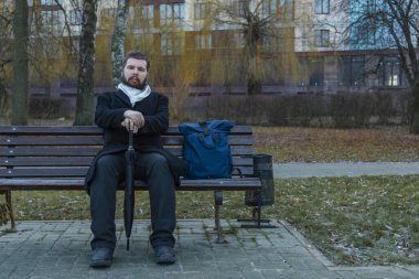 Alacakaranlık karamsar parkta bankta oturan orta yaşlı sakallı adam. Açık alan, depresif fotoğrafçılık.