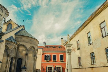 Batı Ukrayna turistik sitesi Lviv ortaçağ kenti arka sokak meydanı manzarası eski binalar ve kilise dış mimari ön cephe ve yumuşak beyaz bulutlu berrak gökyüzü