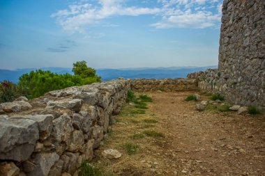 Ortaçağ şatosunun yumuşak odaklı taş duvarları dağlık dağ manzarasındaki kayaların tepesinde harabeler oluşturuyor.
