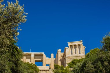 Yeşil ağaçların tepesinde antik antik antik tapınak ve boş mavi gökyüzü olan turizm ajansı posteri, boşluğu kopyala