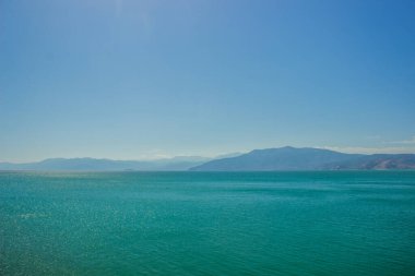 abstract wallpaper landscape of mountain ridge horizon silhouette and sea calm water surface in clear morning foggy weather time, copy space