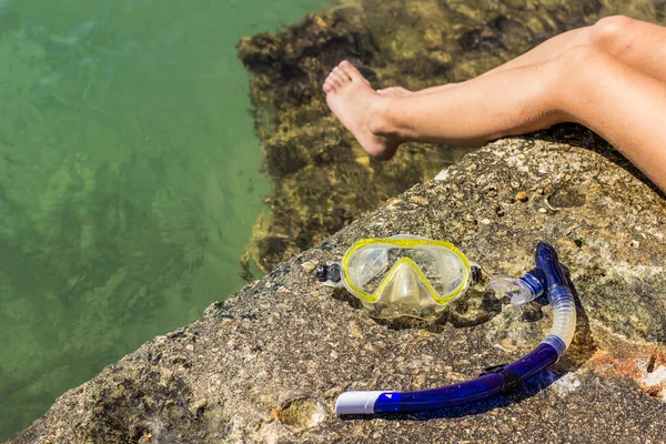 無人の水面と人間の足の背景を持つ南海岸の石の上のシュノーケリングマスク機器オブジェクトの休暇活動的なライフスタイルの概念 — ストック写真