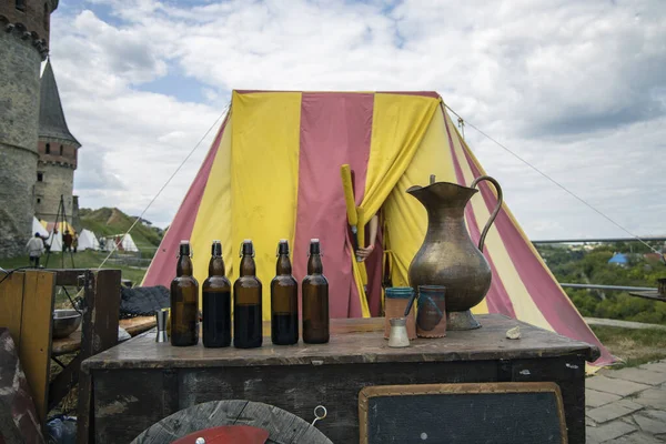 vintage medieval dish and bottles counter table with tent background castle outskirts outside space in cloudy weather time