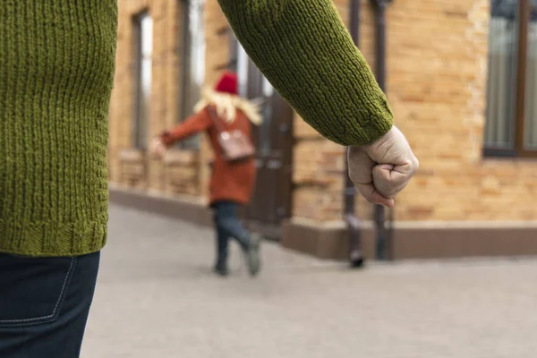 Erkek tacizi mutsuz ilişkiler kavramı sokak fotoğrafçılığı erkek yumruğu ön plan ve çalışan kadın silueti arka plan görünümü