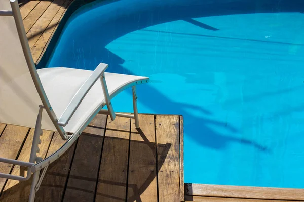 プールサイドの近くにある豪華なリラクゼーションホテルヤードラウンジデッキチェア白い家具ときれいな青い水の夏休みのポスターコンセプト写真 — ストック写真