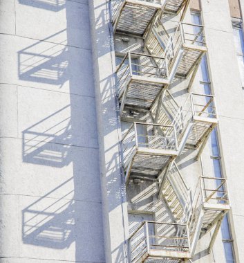 Beton duvarın dışındaki gri bina arka sokaktaki çirkin modern mimari obje çizgileri ve gölgeli şekiller.