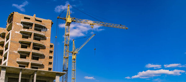 construction building process crane object brick house shape urban landmark photography foreshortening from below on vivid blue sky empty copy space for your text here