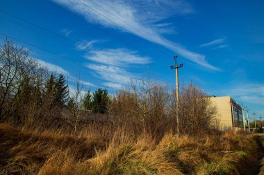 Kirli kırsal kenar mahalleler uzayın çirkin manzarası geçmişteki SSCB ülkesinin kuru sarı, ılık çimenler ve enerji hattı peyzaj sanayi nesnesi ile beton bina arka planı