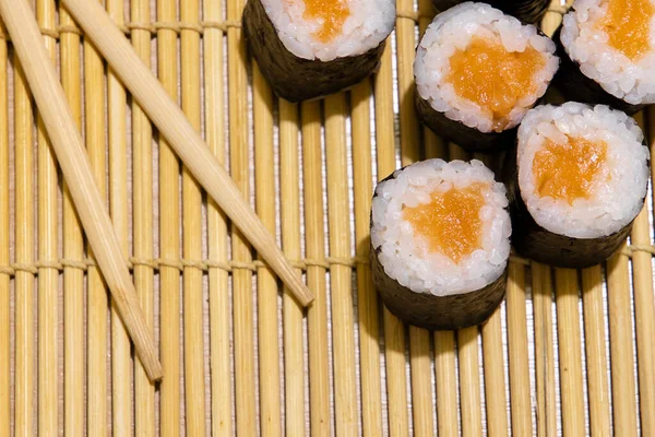 Maki rolos japonês cozinha comida fotografia com paus de madeira no tapete tradicional fundo cozinha wallpaper imagem conceito — Fotografia de Stock