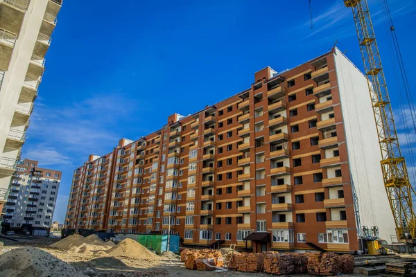 İnşaat süreci, uzun dış cephe, endüstriyel kirli bölge ve vinç, açık hava saatinde, açık mavi gökyüzü ile aşağıdan öngörülmektedir.