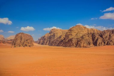 Muhteşem Wadi Rum panoramik manzarası Ürdün Çölü 'nün ünlü gezi yeri kum vadisi ön planı ve yaz zamanı kayalık dağ ufkunun arka planıyla birlikte.