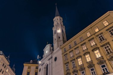 Avusturya 'nın Viyana başkenti Viyana' da akşam saatlerinde, koridor kulesi manzaralı mimari objeyle eski Avrupa bina cephesi duvarı ve pencereleri aydınlatması